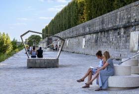 Plusieurs personnes assises sur le mobilier de la promenade Mendès-France, en train de lire ou de contempler le paysage.