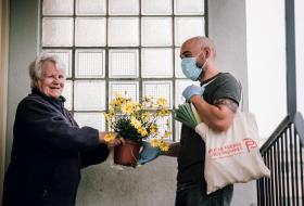 Un homme donne un pot de fleurs à une femme plus âgée.