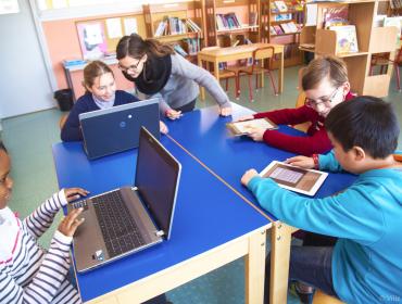 Des enfants s’exercent sur des ordinateurs et des tablettes.