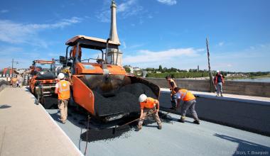 Des ouvriers travaillent sur le nouveau revêtement de la chaussée du Pont Jacques-Gabriel.