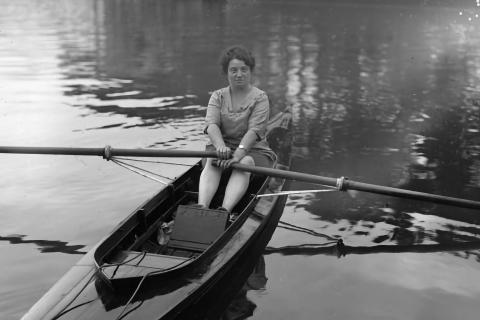 Alice Milliat sur une barque en train de ramer tout en souriant à l’objectif.