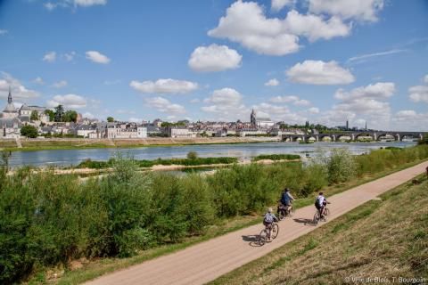 Trois cyclistes circulent sur la piste de la Loire à vélo et se dirigent vers le pont Jacques-Gabriel.