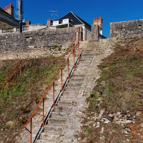 Une rampe métallique le long d’un escalier reliant la levée à un chemin pavé en bord de Loire.